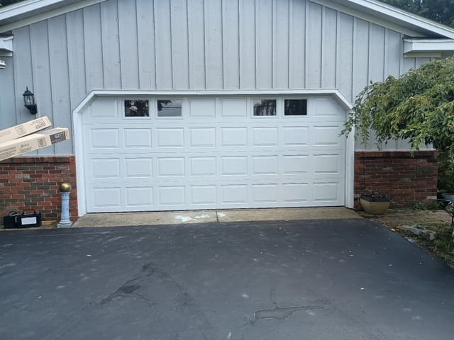 White raised-panel double garage door on a home with board-and-batten siding