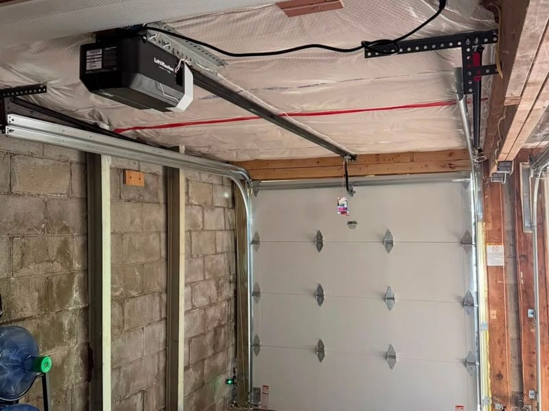 Interior of a garage with a new insulated door, tracks and a LiftMaster opener installed