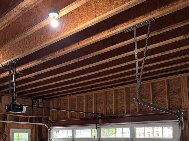 A ceiling-mounted LiftMaster garage door opener and rail inside a wood-framed garage