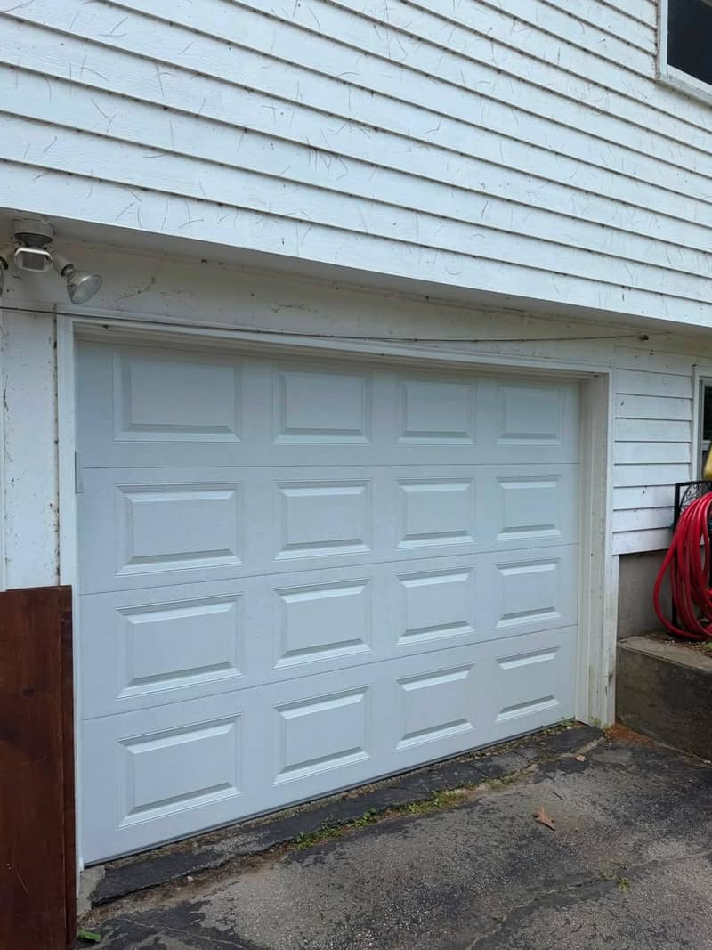 New clean white raised-panel double garage door on the same opening